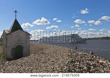 Goritsy, District of Kirillov, Vologda region, Russia - August 10, 2015: Passenger ship Maxim Litvinov passes near Goritsky Voskresensky monastery on the Sheksna River in Vologda Region