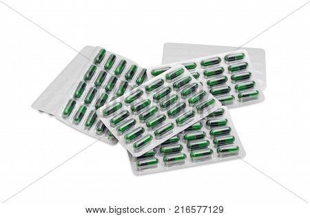 Several blister packs with green capsules of dietary supplements on a white background