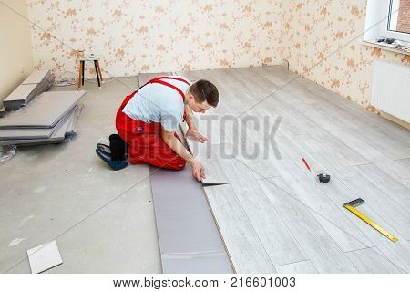 handyman laying down laminate flooring boards while renovating a house
