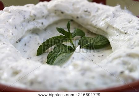 Closeup view of labneh with garlic and mint in a bowl.
