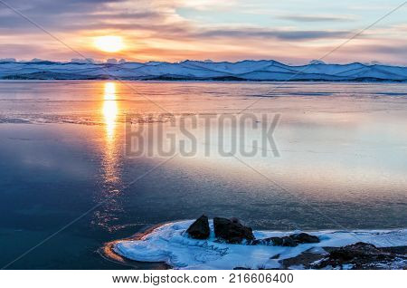 Ice floes floating on the fog water in the lake Baikal and hill, Russia. Sunset