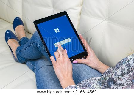 Sankt-Petersburg Russia December 3 2017: Woman Hands using iPad pro with Facebook homepage on monitor screen. Facebook the biggest social network website. Homepage of Facebook.com on tablet computer.