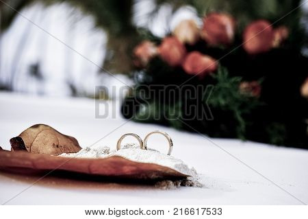Wedding rings in sand on tropical beach