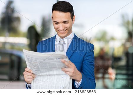 young businessman reading newspaper at airport