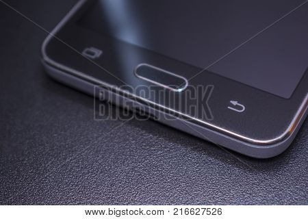 Touch smartphone in black on a black matte background.