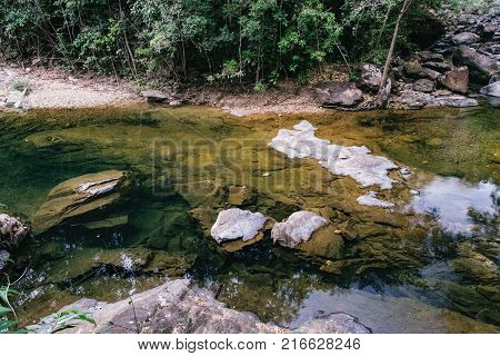 Small mountain stream in the shade of the tropical forest with snag tree in the foreground Mu Koh Chang National Park, Chang island, Thailand. Path to the Khlong Phlu waterfall. Natural background.