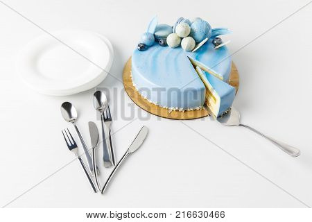 top view of blue cake surrounded by flatware isolated on blue
