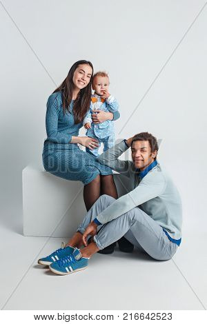 A happy family of afro man and caucasian woman and child on white studio background