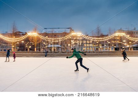Outdoor Shot Of Unexperienced Male Skater Uses Skate Aid For Go Skating On Ice, Being In Good Mood,