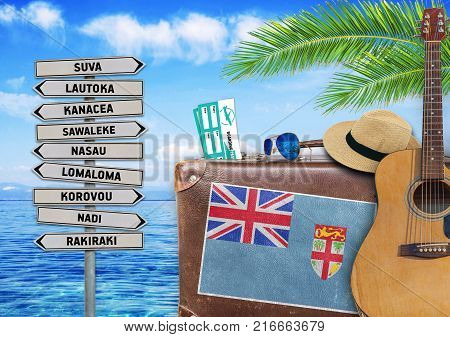 Concept of summer traveling with old suitcase and Fiji town sign
