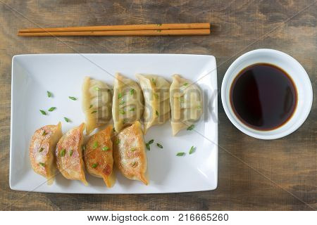 Eight boiled or fried jiaozi or gedza served with soy sauce. Selective focus.