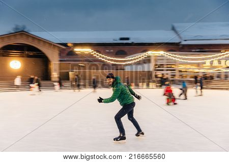Young Male Begginer Learns Skating With Help Of Special Figure, Leans At It, Being On Ice Rink Cover