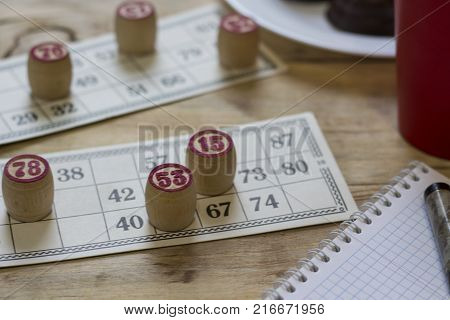 Cards And Chips For Playing Bingo On A Wooden Table. Cup With Coffee