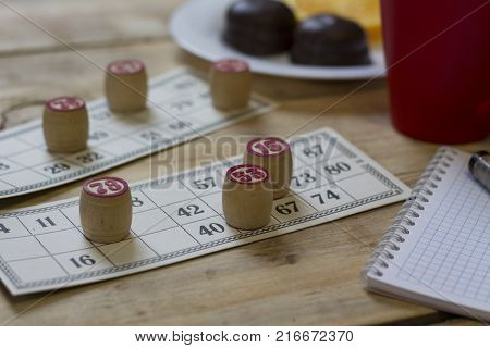 Cards And Chips For Playing Bingo On A Wooden Table. Cup With Coffee