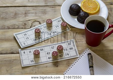 Cards And Chips For Playing Bingo On A Wooden Table. Cup With Coffee