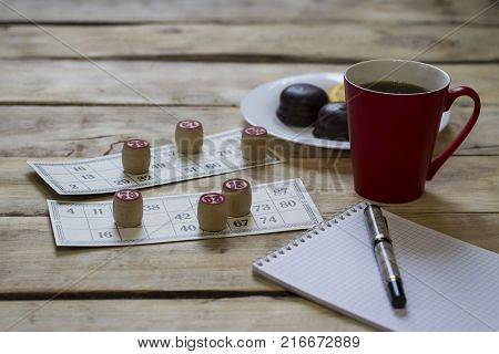 Cards And Chips For Playing Bingo On A Wooden Table. Cup With Coffee