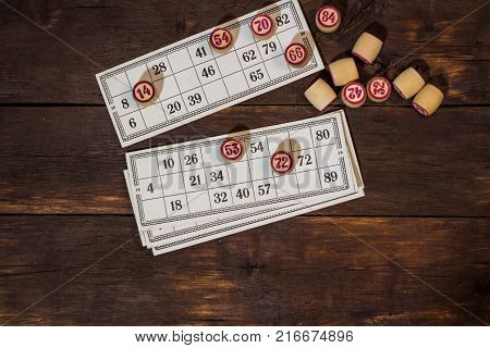 On A Wooden Bingo Table Game, A Cup With A Coffee, A Biscuit And An Orange Slice