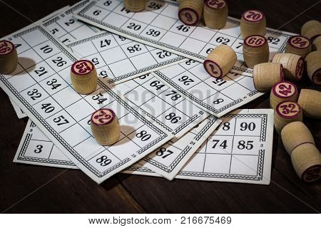 On A Wooden Bingo Table Game, A Cup With A Coffee, A Biscuit And An Orange Slice