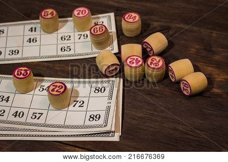 On A Wooden Bingo Table Game, A Cup With A Coffee, A Biscuit And An Orange Slice