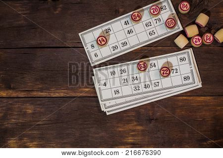 On A Wooden Bingo Table Game, A Cup With A Coffee, A Biscuit And An Orange Slice