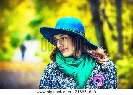 Thoughtful brunette girl walking at park in autumn