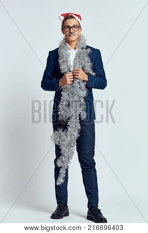 business man in full growth with tinsel on his neck, bright background, holiday, new year, christmas.