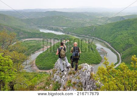 Hikers on top of a mountain enjoy the beautiful view of nature, forest and river in valley. View on meanders of Morava river  from Kablar, Serbia