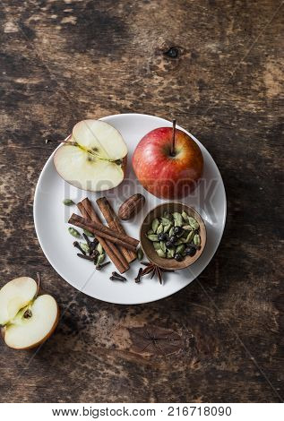 Ingredients for cooking spicy apple tea with spices cinnamon anise cardamom cloves on wooden table top view. Warming winter drink