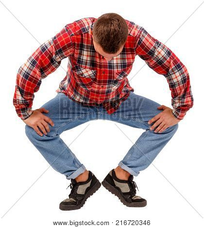 Young man in studio posing, lowering his head, performing plie at first swivel position, dressed in red plaid shirt and jeans, isolated on white background