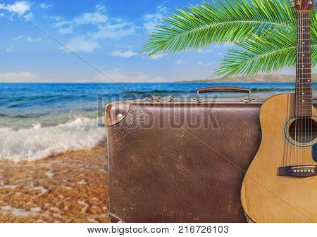 Concept of summer traveling with old suitcase and guitar