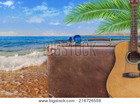 Concept of summer traveling with old suitcase and guitar