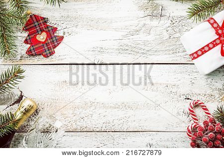 Christmas composition with fir tree branches and red christmas decorations on white wooden background, top view with copy space
