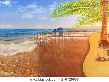 Concept of summer traveling with old suitcase and guitar and burning sun