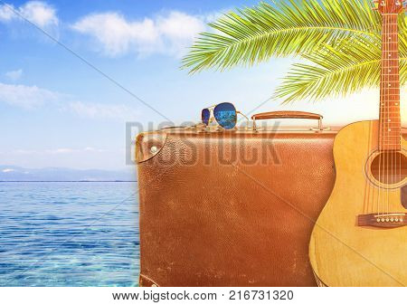 Concept of summer traveling with old suitcase and guitar and burning sun