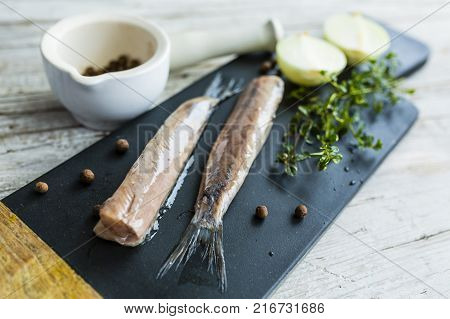 Prepared fresh salted herrings on a stone board.