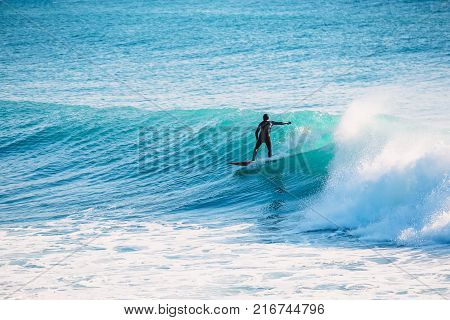 Surfer ride on blue wave. Winter surfing in ocean