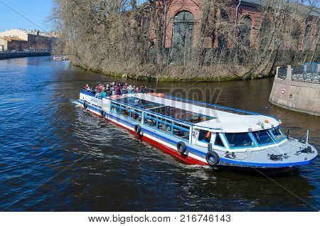 SAINT PETERSBURG RUSSIA - MAY 2 2017: Unknown tourists are on sightseeing boat on Moika River near forest depot St. Petersburg Russia