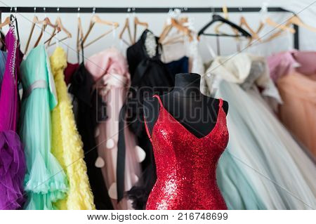 Many ladies evening gown long dresses on hanger in the dress rent shop for the wedding day or photo session. Dresses rental concept. Selective focus. Ball gown rental concept