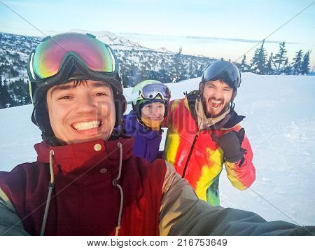 Group of happy friends having fun. Snowbarders and skiers group team friendship. Mountain top.