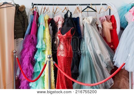 Many ladies evening gown long dresses on hanger in the dress rent shop for the wedding day or photo session. Dresses rental concept. Selective focus. Ball gown rental concept
