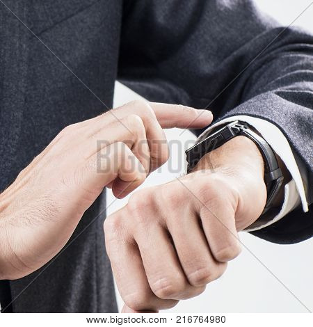 Closeup hands of man using his smartwatch over gray background.
