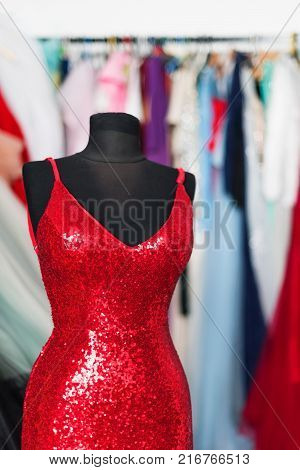 Red evening dress on background of long dresses on hanger