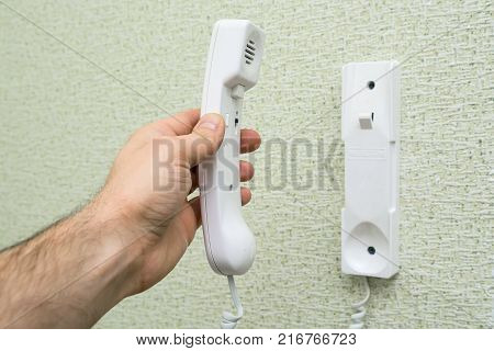 Close up male h and holding intercom installed in flat