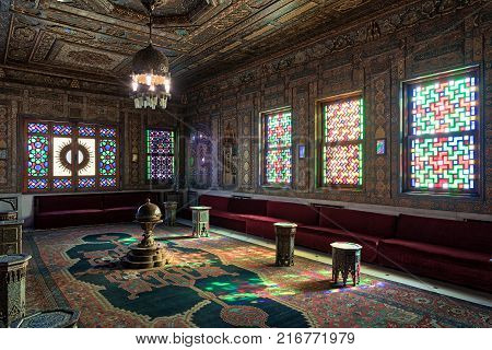Cairo Egypt - December 2 2017: Manial Palace of Prince Mohammed Ali. Syrian Hall with ornate wooden wall and ceiling windows with colored stained glass and Ottoman Empire logo old ornate chandelier red couches tea tables and ornate carpet