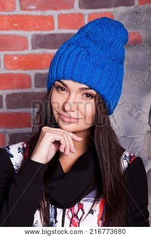 girl in hat and fur coat, against a brick wall background