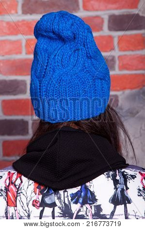 girl in hat and fur coat, against a brick wall background