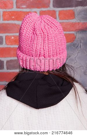 girl in hat and fur coat, against a brick wall background