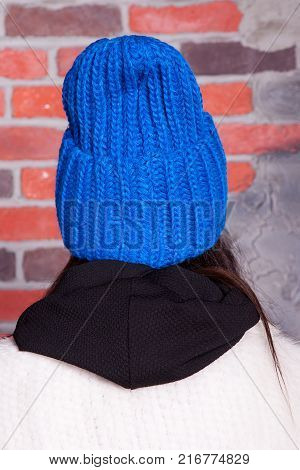 girl in hat and fur coat, against a brick wall background
