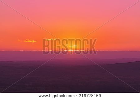 A warm pink and orange sunset landscape, with the sun setting over UK Shropshire rural countryside.