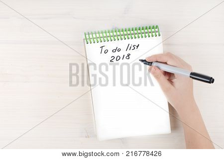 A to-do list in a notepad on spirals. Place for text. A girl's hand holds a marker. Mock ap.